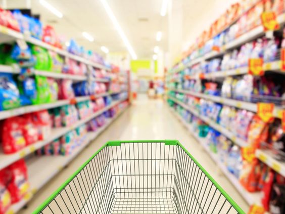 Keranjang belanja di lorong supermarket grosir penuh produk kebutuhan sehari-hari di Indonesia tahun 2025