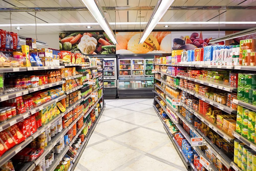 Rak supermarket penuh berbagai produk makanan dan minuman sebagai contoh bisnis grosir di Indonesia.